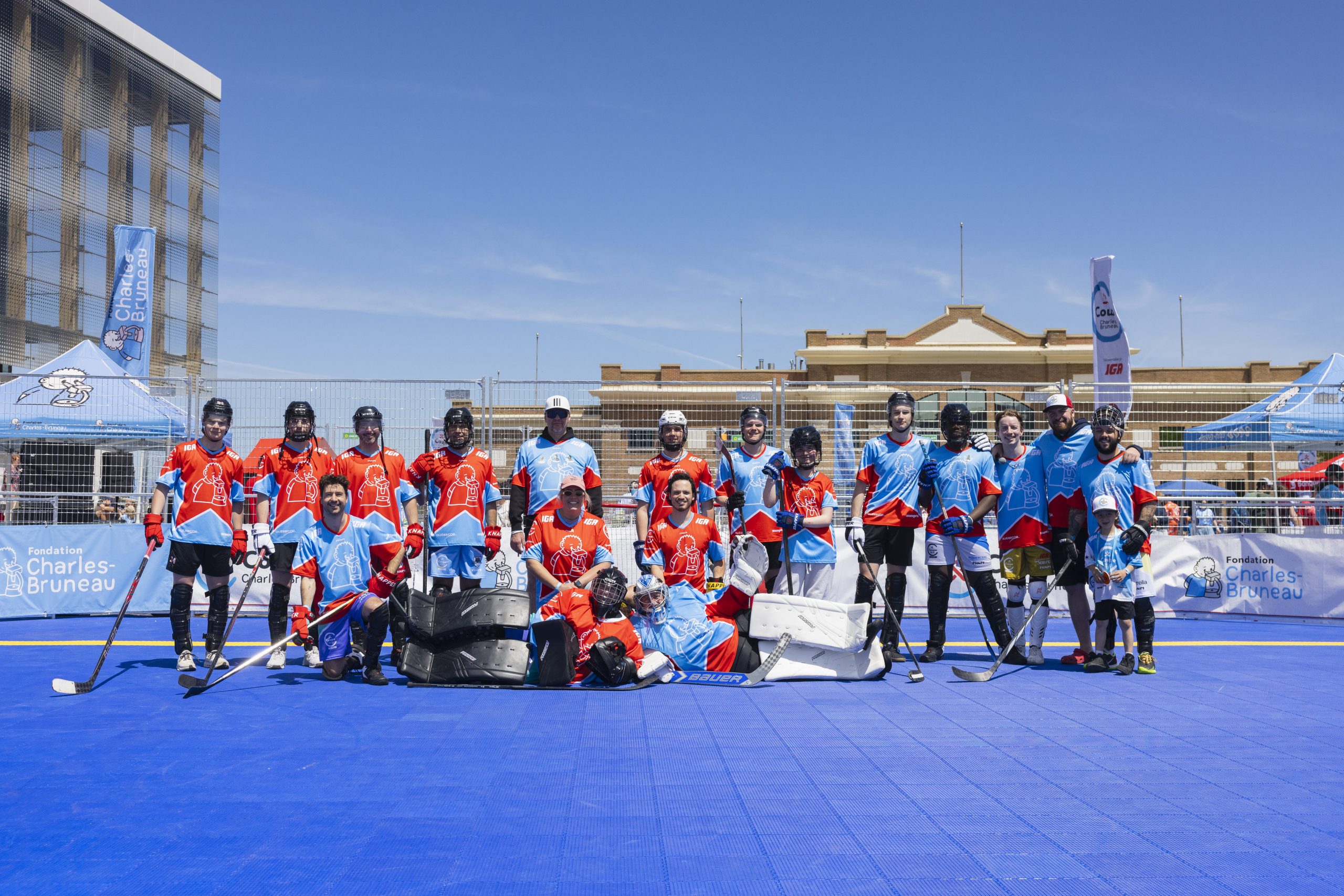 Équipe de hockey-balle en uniformes rouges et bleus pose sur la patinoire bleue lors de la Coupe Charles-Bruneau.