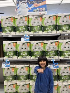 Liam tend le poing vers la caméra devant des étalages Cascades Fluff sous une affiche 1 achat = 1 don.